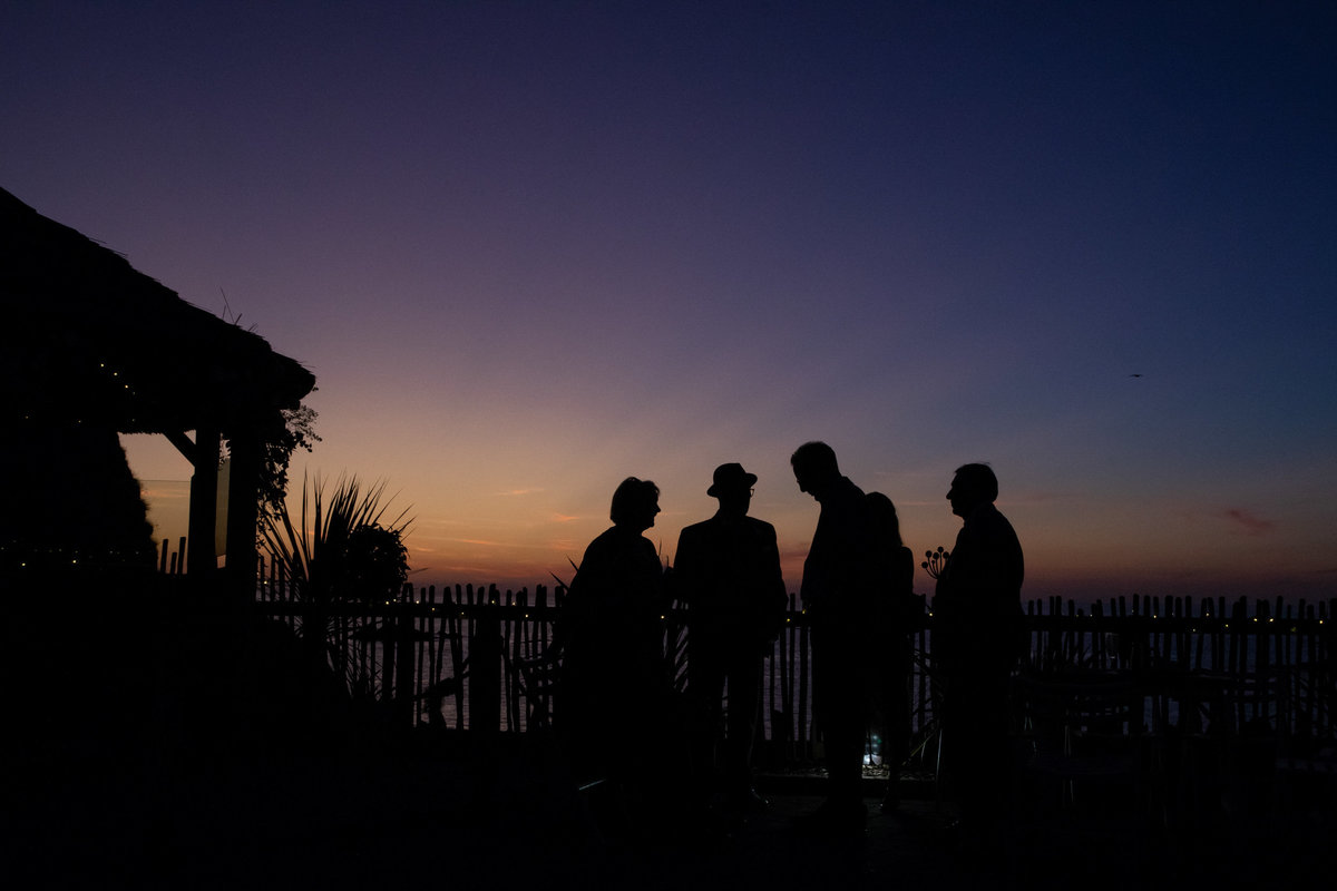 Silhouette  og guests talking at sunset in a natural wedding photo from Tunnels Beaches in Devon