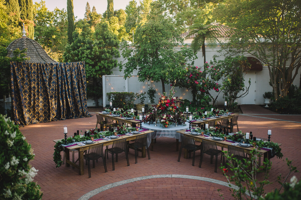 A uniquely designed floorplan, this outdoor bridal shower set up with farm house tables and moody florals is a great addition to the Gardens Courtyard.