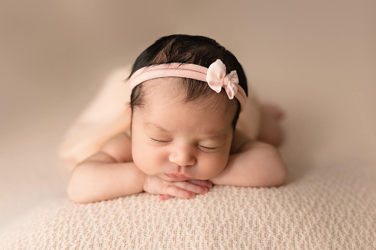 Newborn girl posed on her hands during her Newborn Photography Session at Jennifer Brandes Photography.