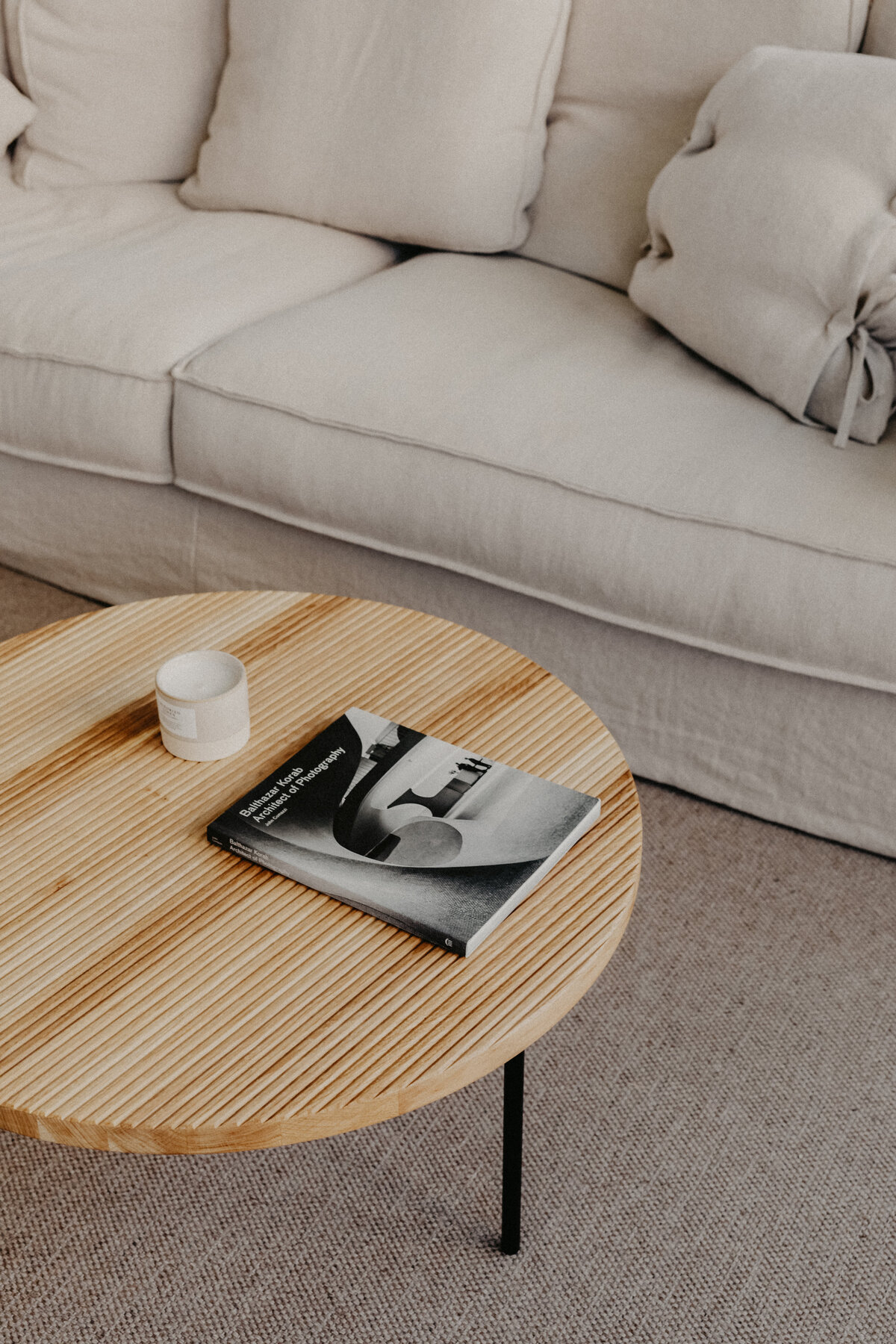 kaboompics_Wooden coffee table - book - candle - linen sofa - pillows - carpet