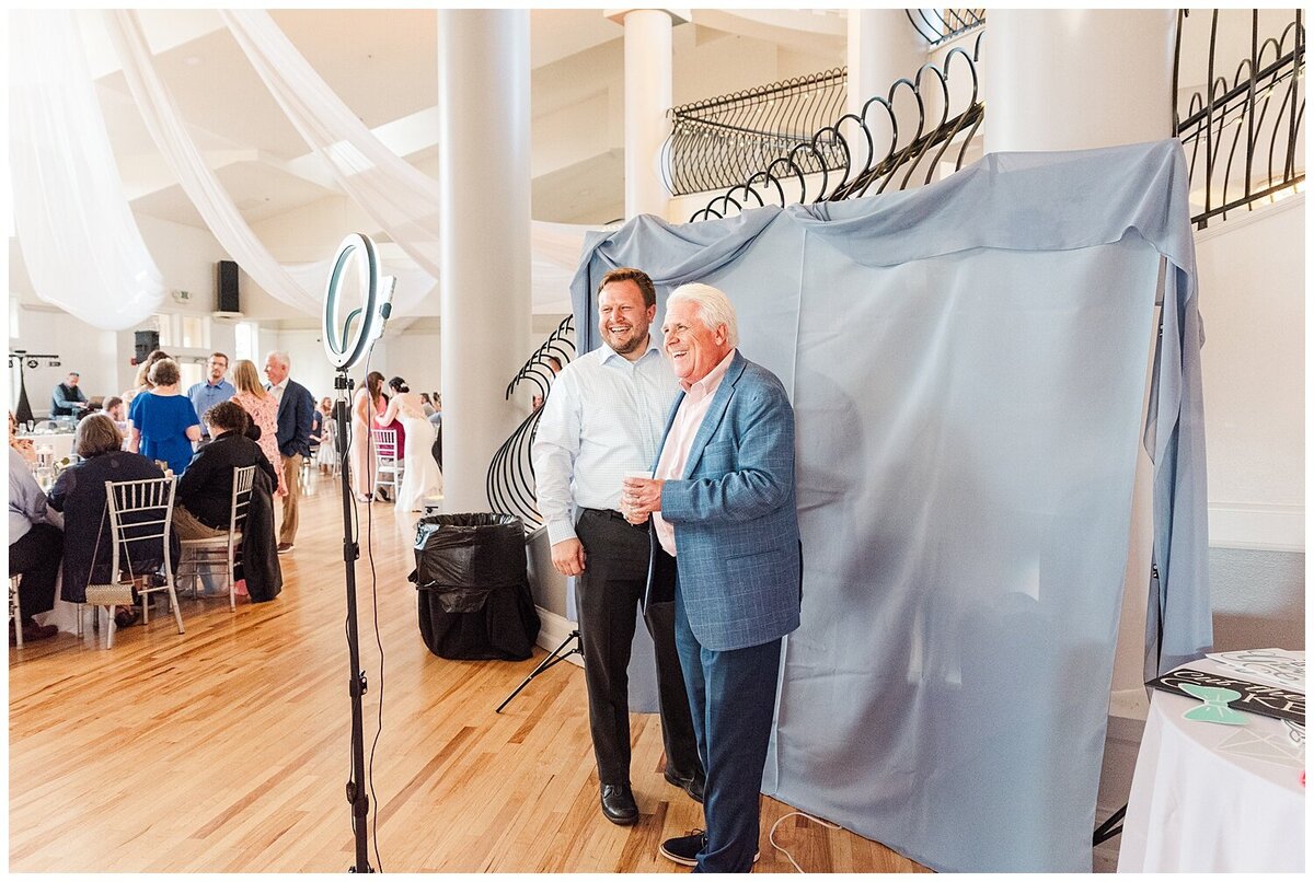 Guests take photos of themselves with a selfie booth at a wedding reception