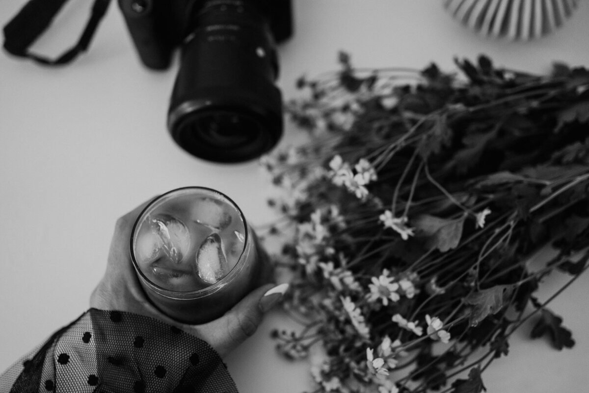 flat lay of florals, camera, and iced coffee