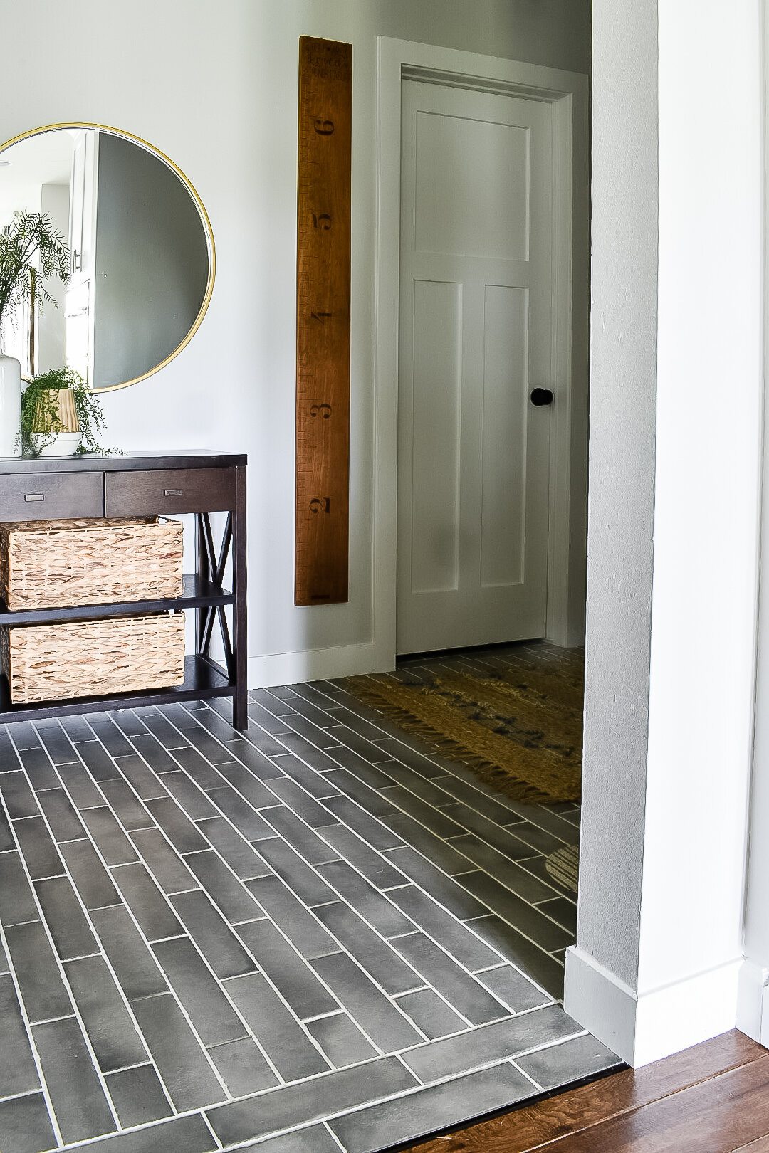 A small entryway with grey tile and a wooden console
