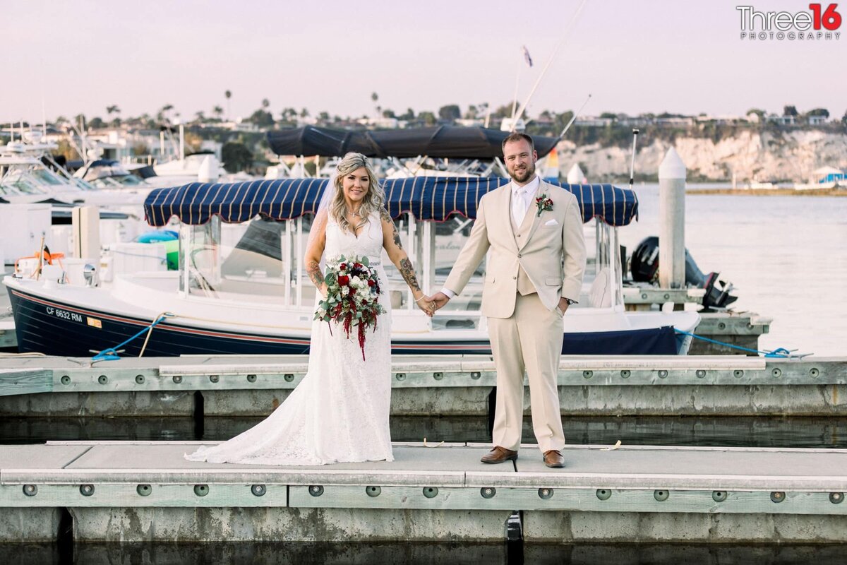 Bride and Groom hold hands during photo session on the docks at Newport Dunes