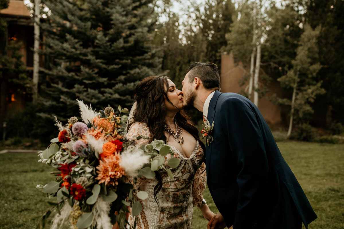 bride and groom kissing in a field at their Taos New Mexico wedding venue