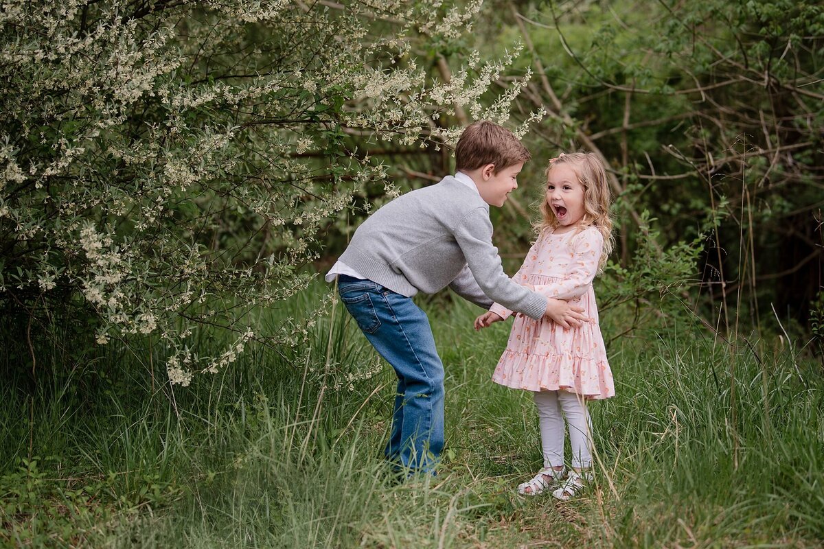 little girl with shocked expression holding hands with brother in spring outdoor scene