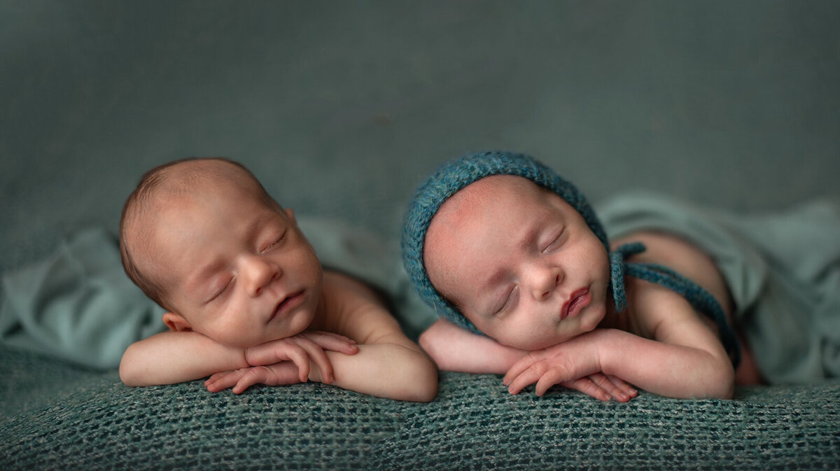 twin newborns laying on their hands at st louis newborn session