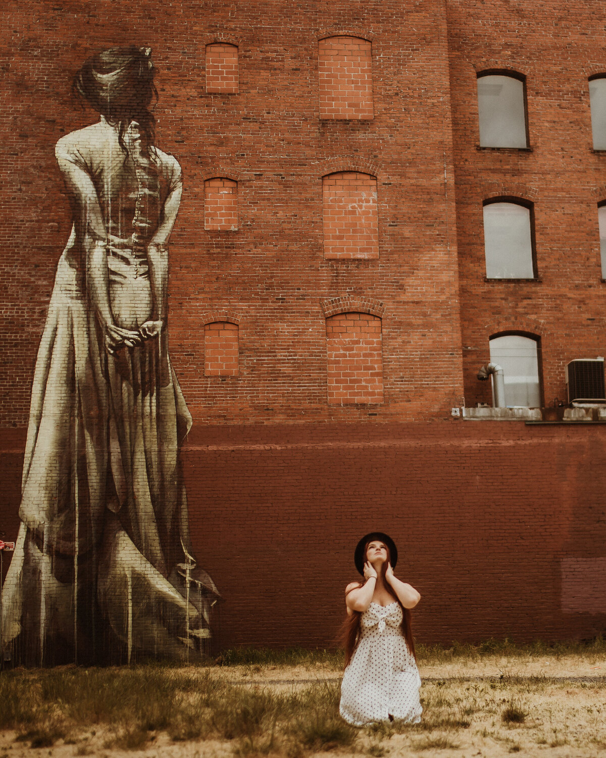 Lifestyle brand creative  headshot of woman kneeling in front of brick building