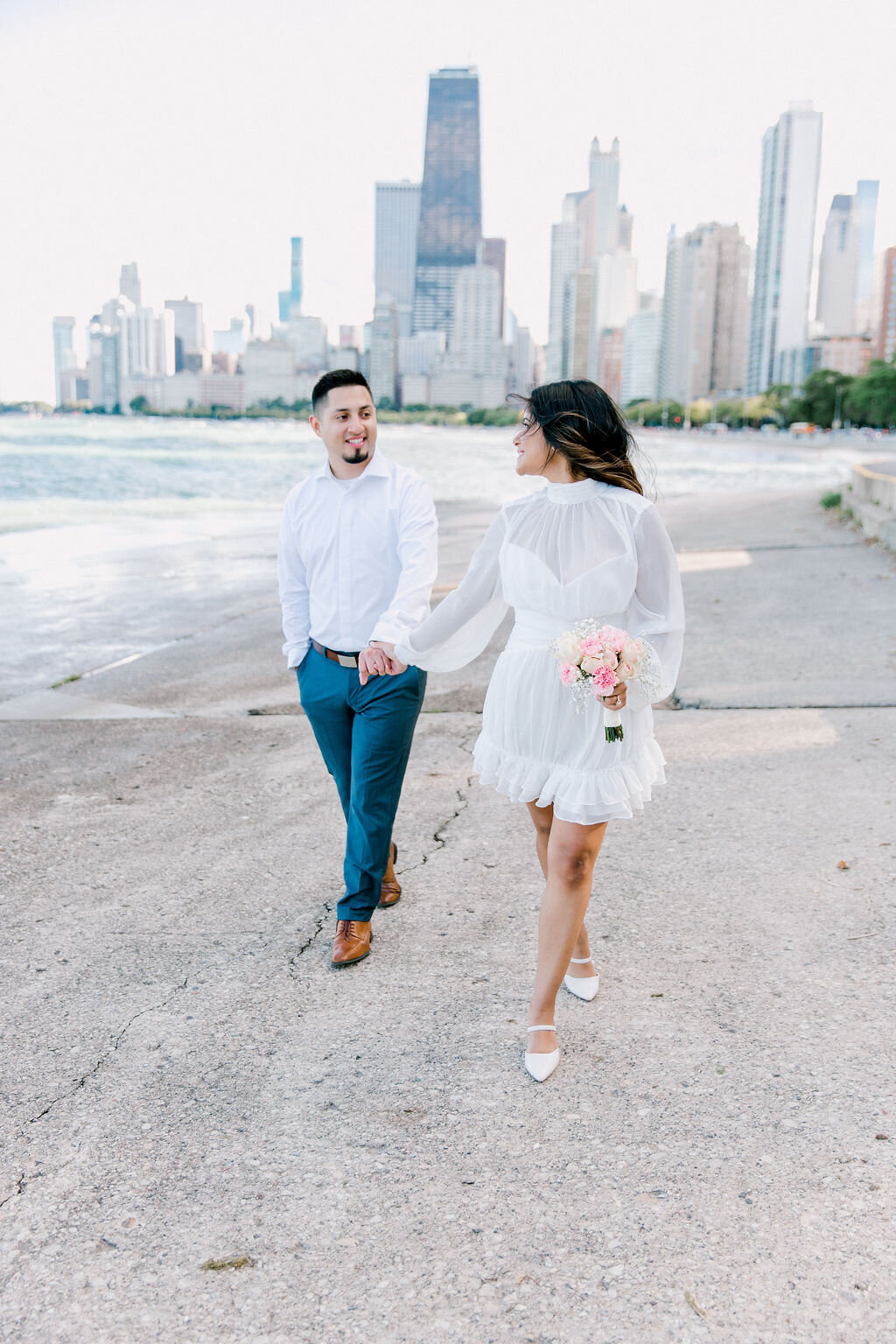 Joyful bride and groom sharing a laugh, with Chicago's iconic skyline, including the Willis Tower, forming a majestic backdro