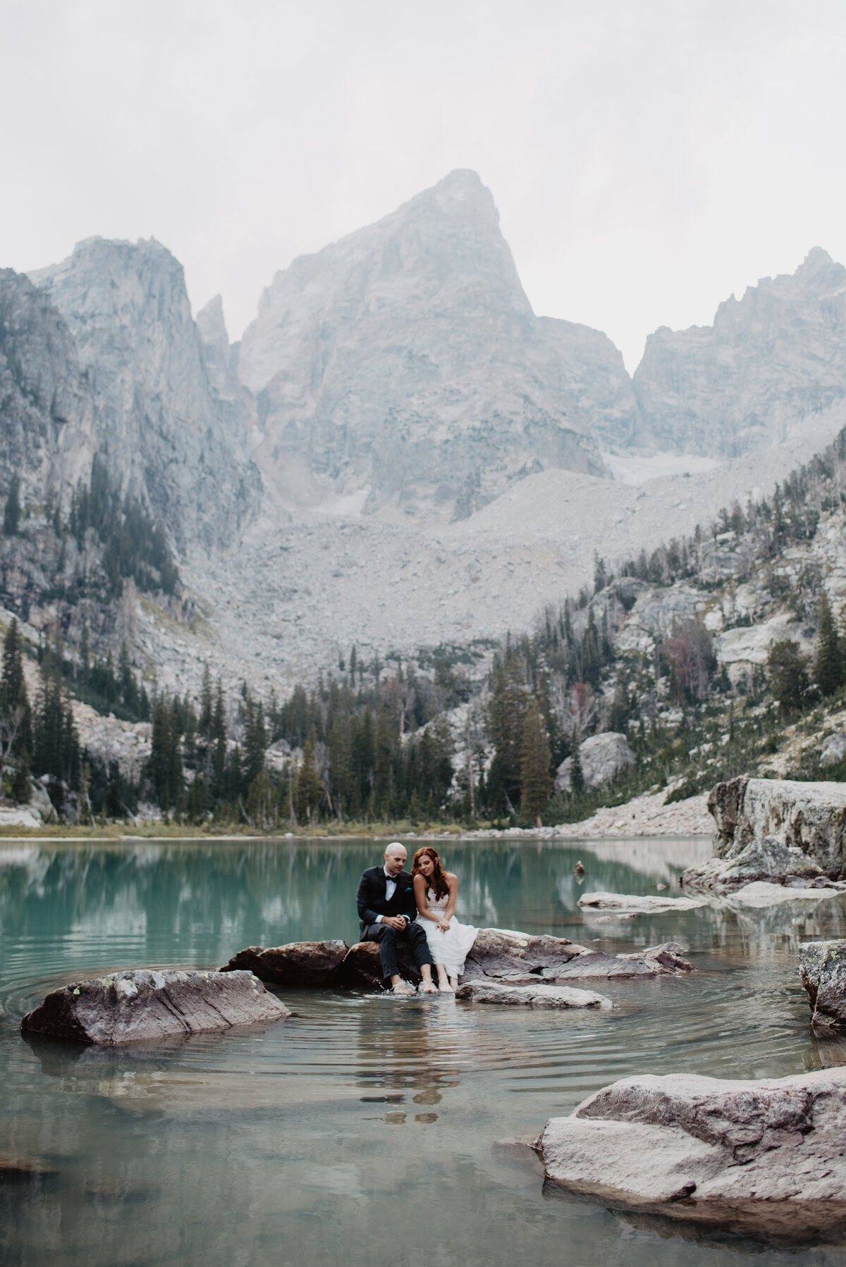 Jackson Hole Photographers capture couple sitting on rock together in Grand Teton elopement