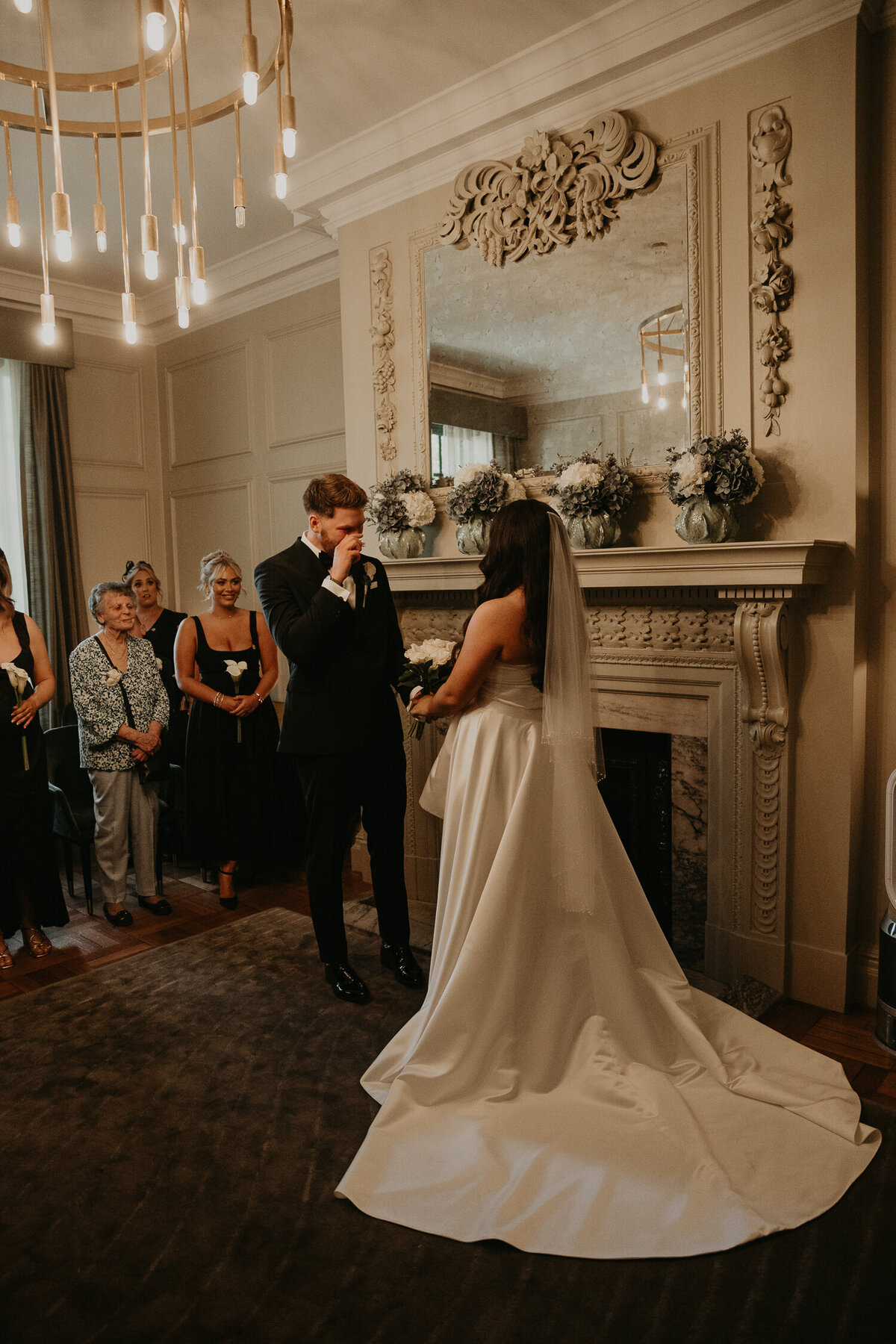 Groom cries as he sees his bride for the first time at their wedding ceremony at The Old Marylebone Town Hall. 
