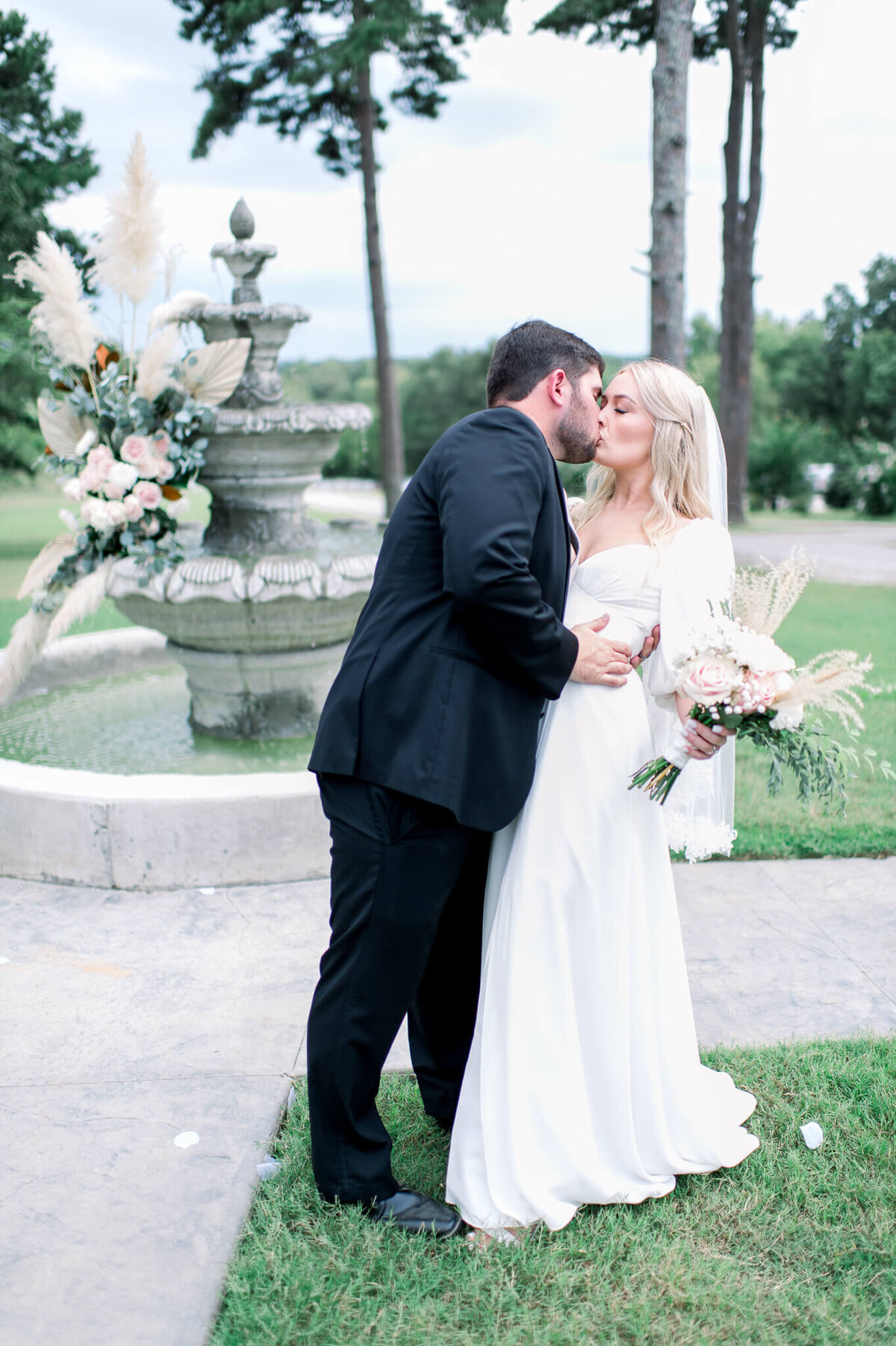 bride and groom kiss in front of water fountain