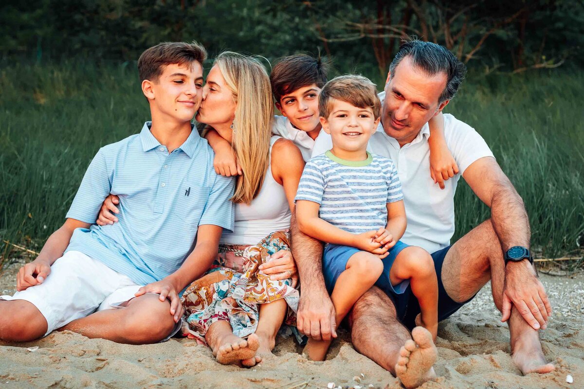 family sitting in sand during long island family photos on beach