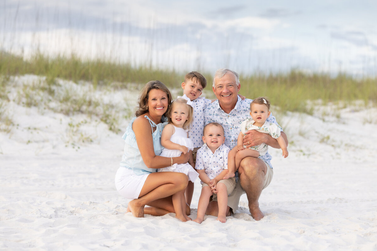 Grand parents kneeling down with their grandchildren around them at the beach in Inlet Beach Florida.