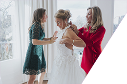 Een bruid wordt in haar trouwjurk van Viktor & Rolf geholpen door haar moeder in rode jurk en haar zus in groene jurk tijdens haar bruiloft in Rotterdam