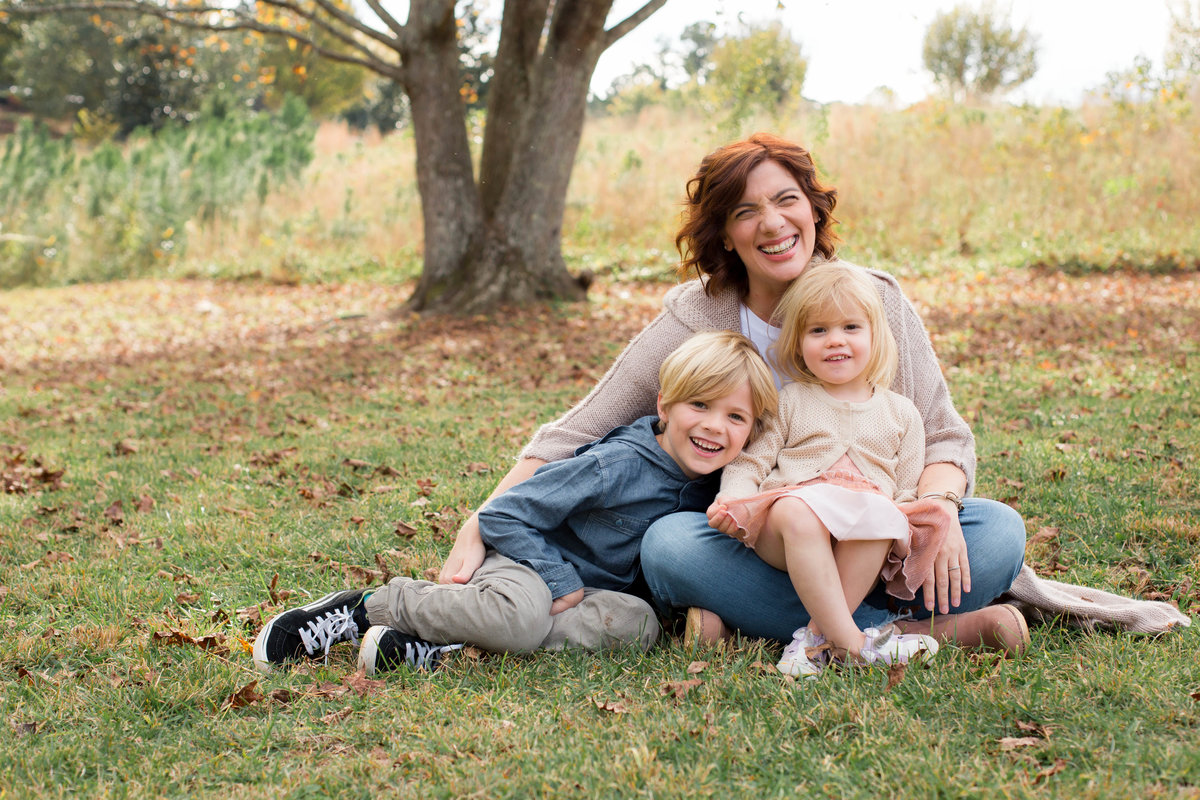 Family sits in front of tree for lifestyle photo