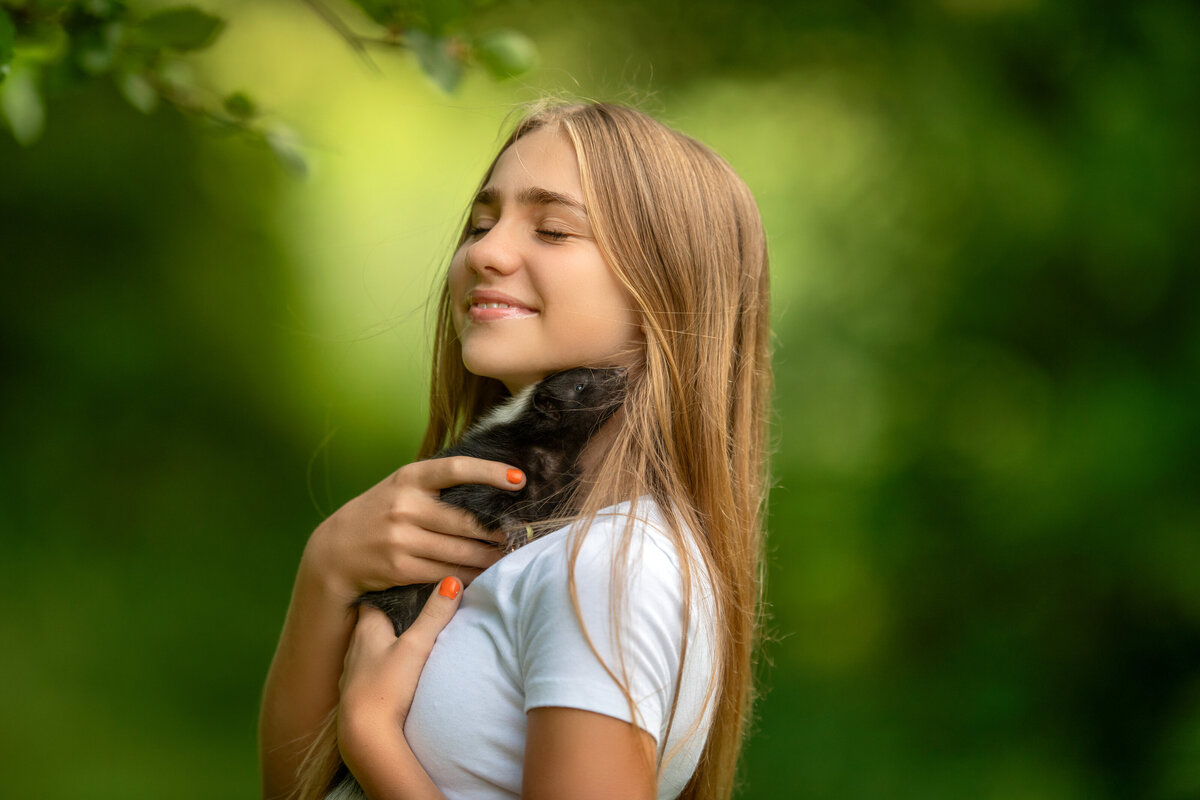 Teenager snuggling with baby skunk during outdoor photoshhot