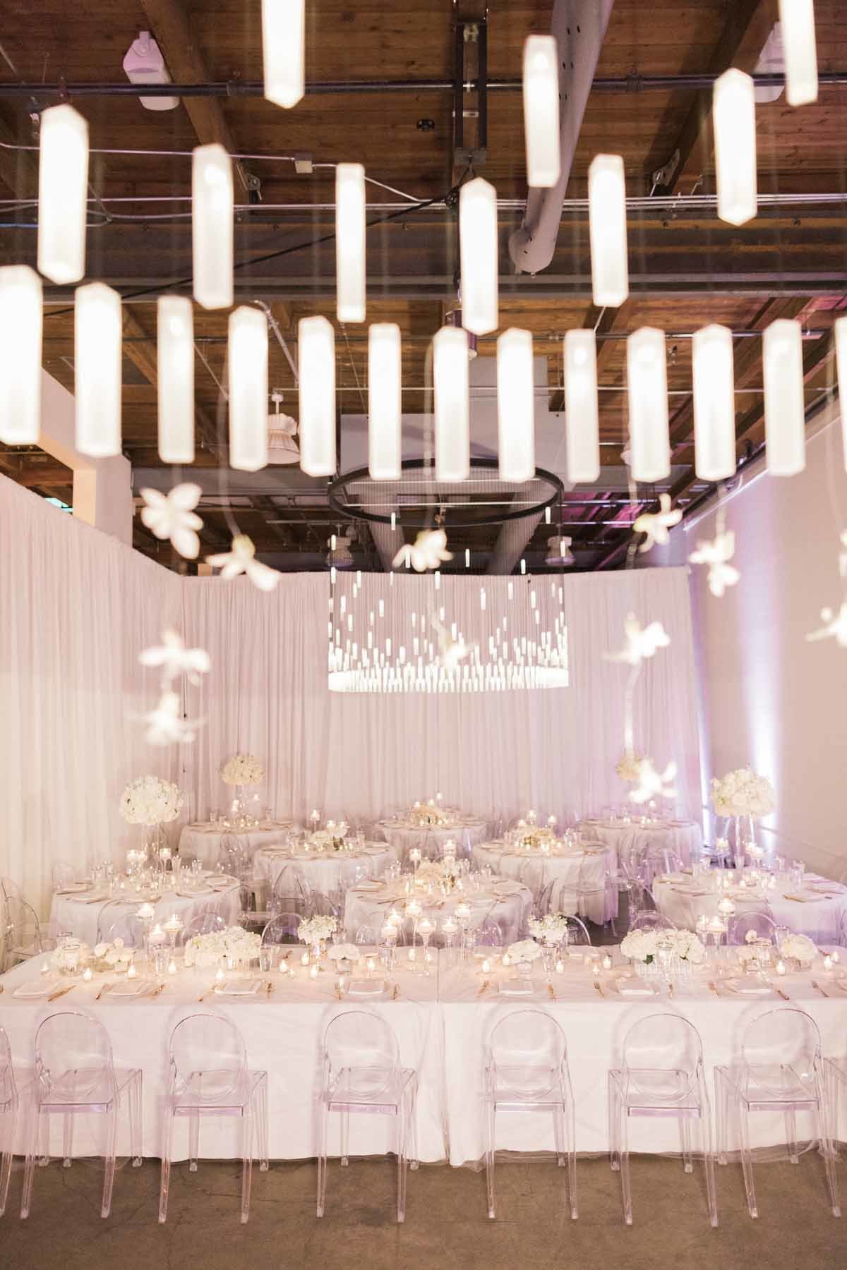 Chandelier with delicate white orchids hanging from it suspended over head table