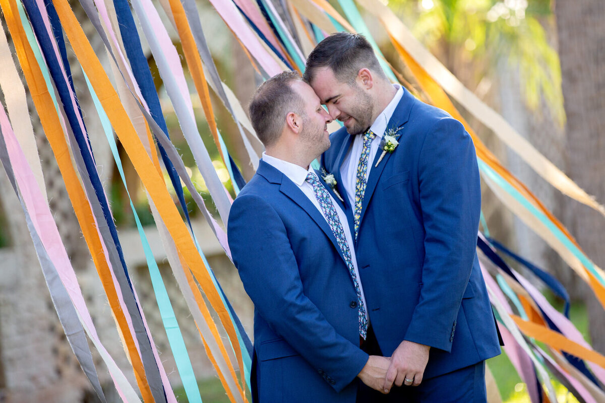 Two grooms embrace on their wedding day at Atalaya Castle in Huntington Beach State Park