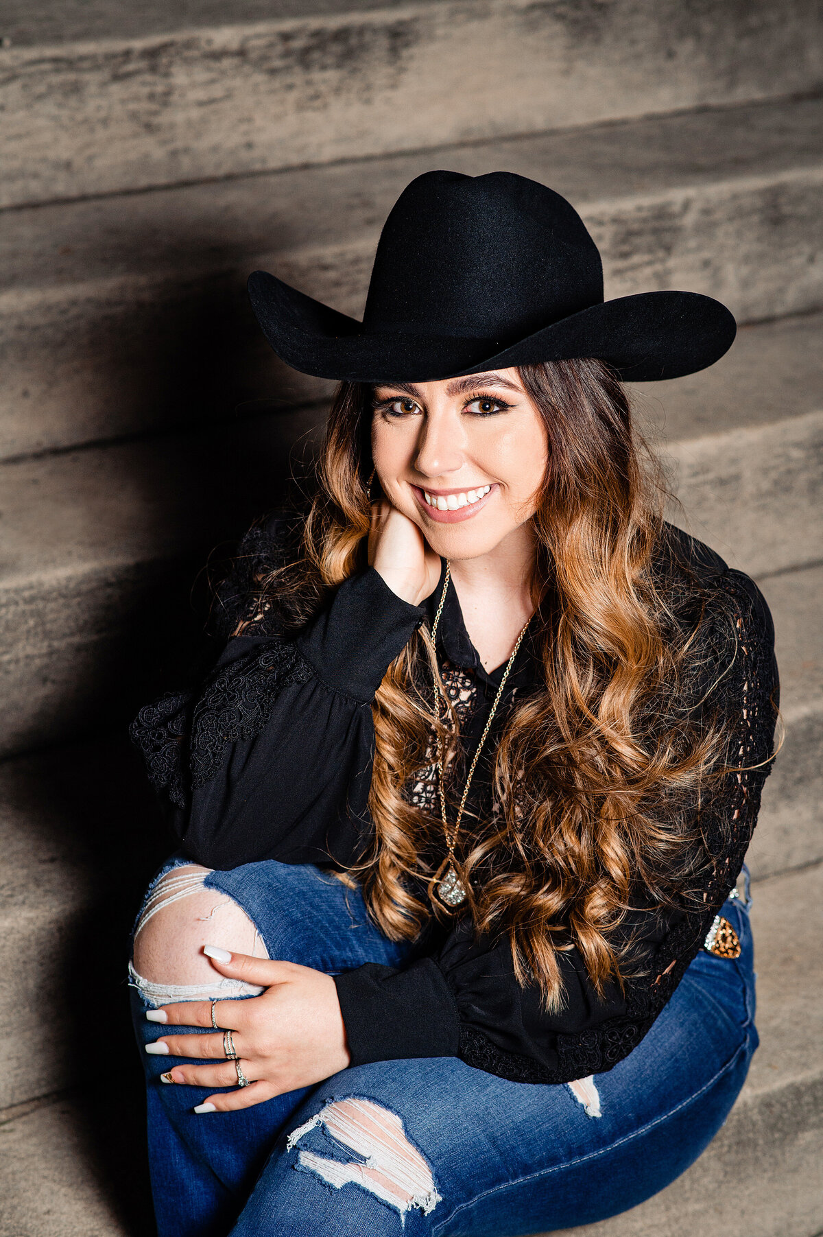 Girl wearing black cowgirl hat and smiling at the camera