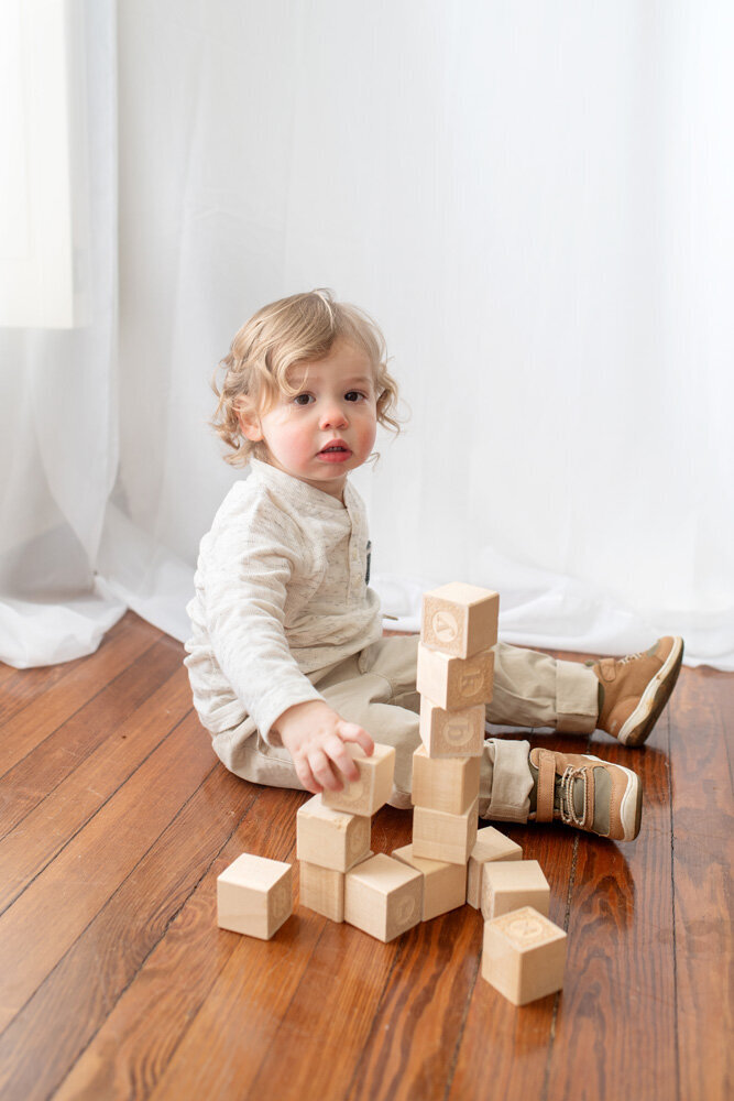 Family session of toddler sitting with toy blocks