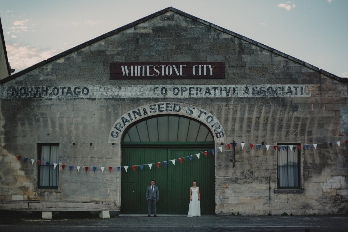 Bride and groom in front of Whitestone city building in Oamaru