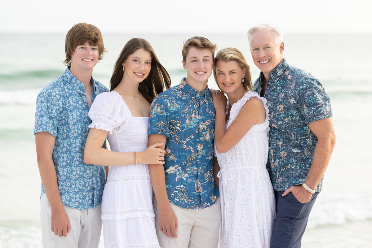 Parents with their teenagers smiling together at the beach