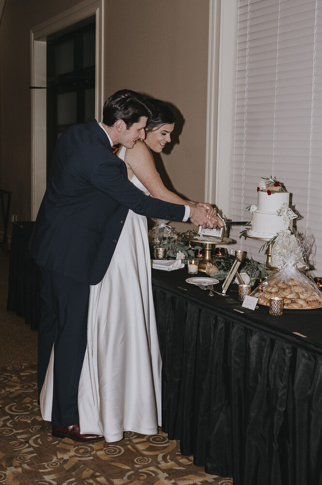 groom helping bride cut the wedding cake