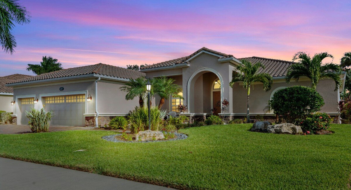 A home at twilight with it's lights on.  there is a lawn with green grass.  This photo has been virtually altered to have a virtual twilight look.