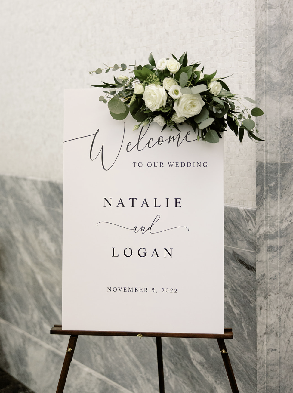 Elegant minimalist welcome sign decorated with greenery and white roses greets Chicago wedding ceremony guests.