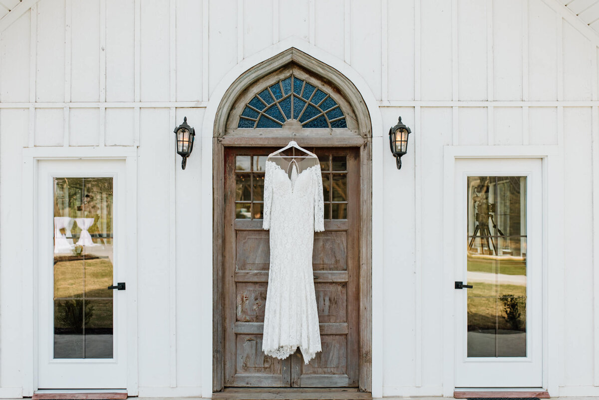 wedding dress hanging on chapel door at Four Fifteen Estates in New Boston, TX
