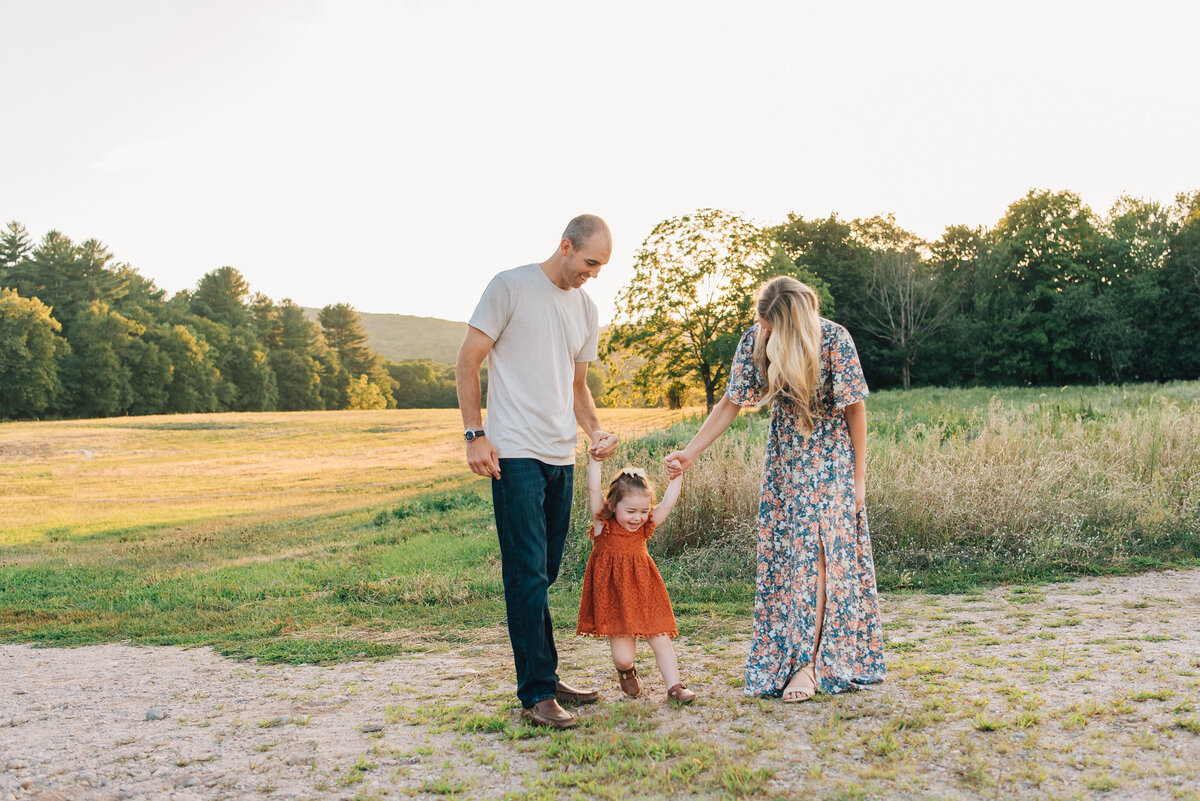Family of three playing in field at sunset