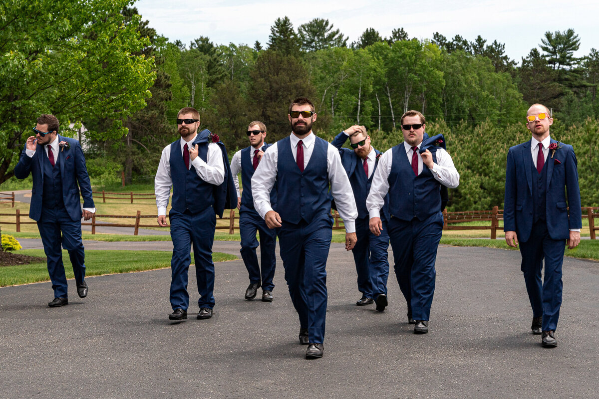 Groom and wedding party walk down a path on wedding day.