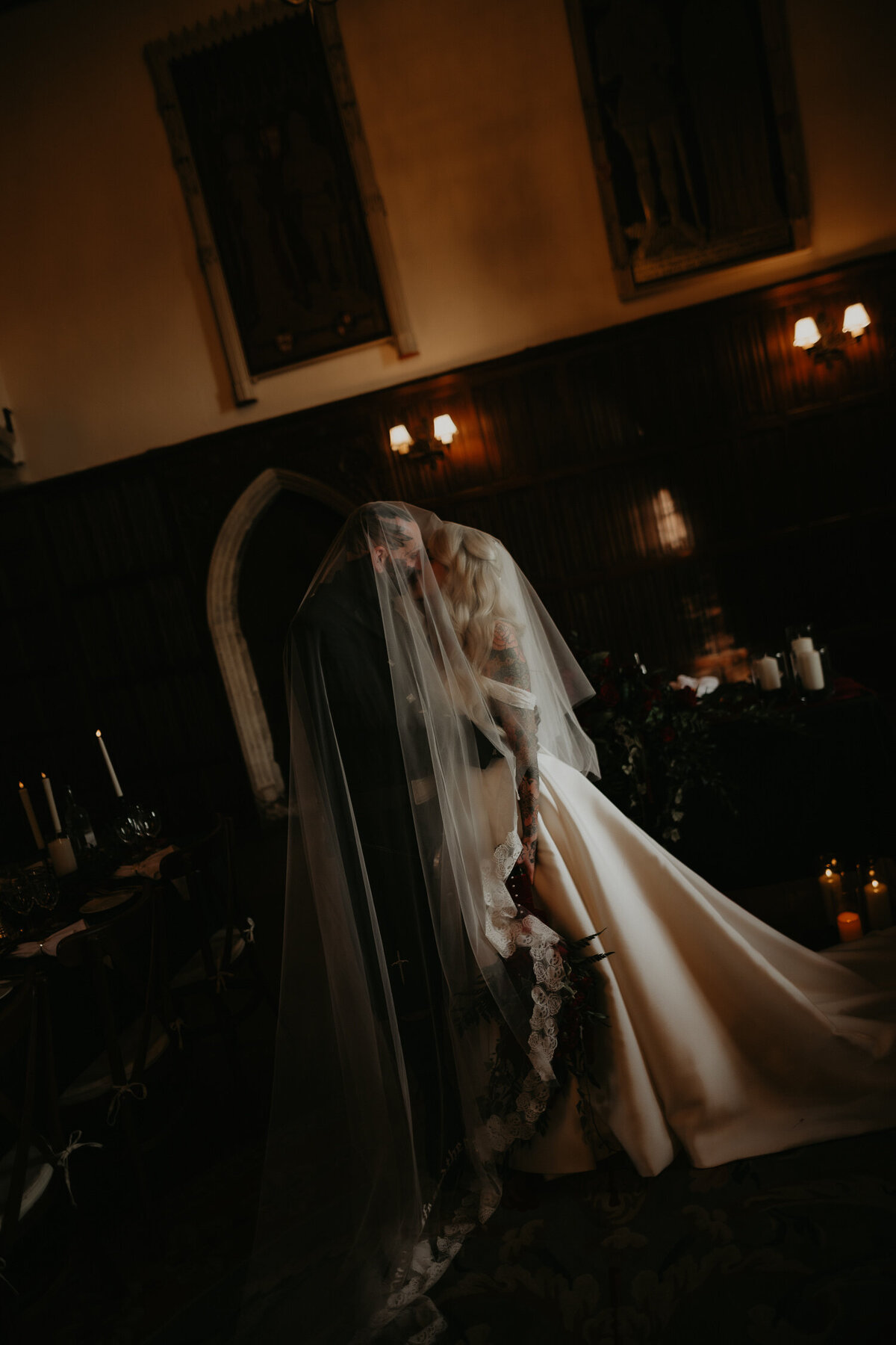 A tattooed wedding couple covered by a large wedding veil at Lympne Castle in Kent.