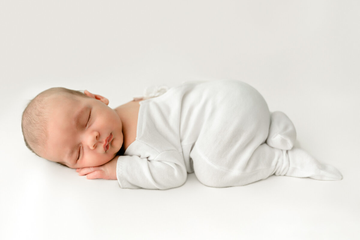 Serene slumber: a peaceful newborn asleep in a cozy white outfit. Taken by Twin Cities Newborn Photographer, Fig and Olive Photography