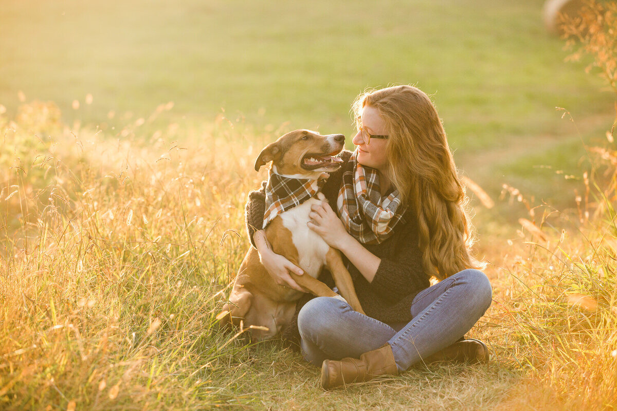 girl and pet dog in field at sunset