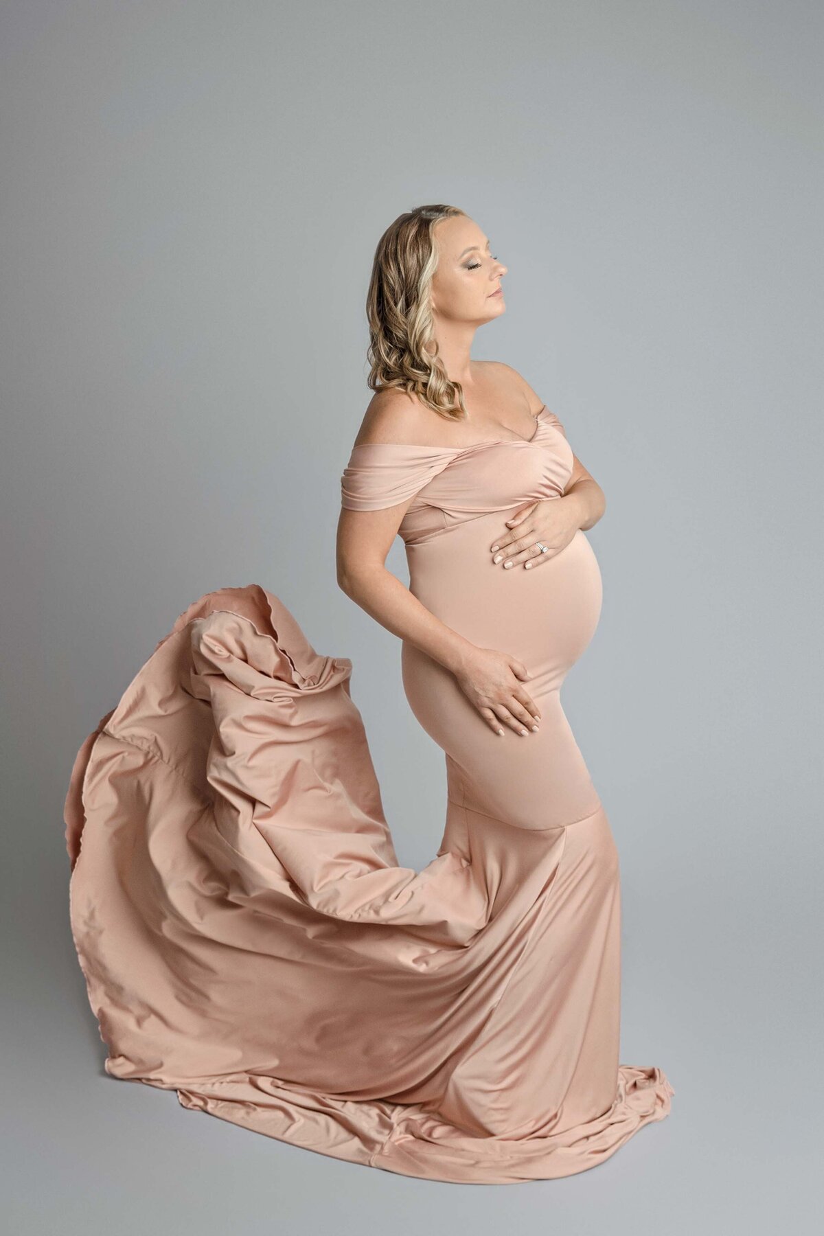 Expecting Mom Holding Belly Dressed In Pink Flowing Dress