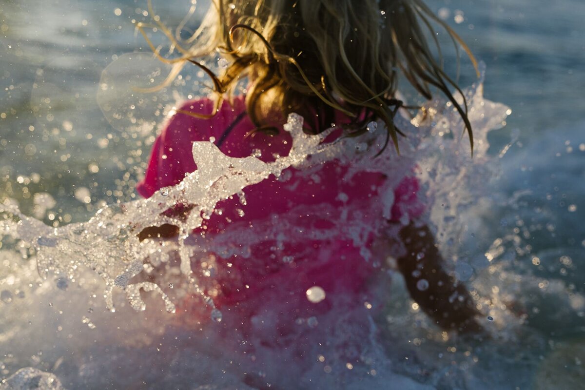A little girl splashes in the Ocean.