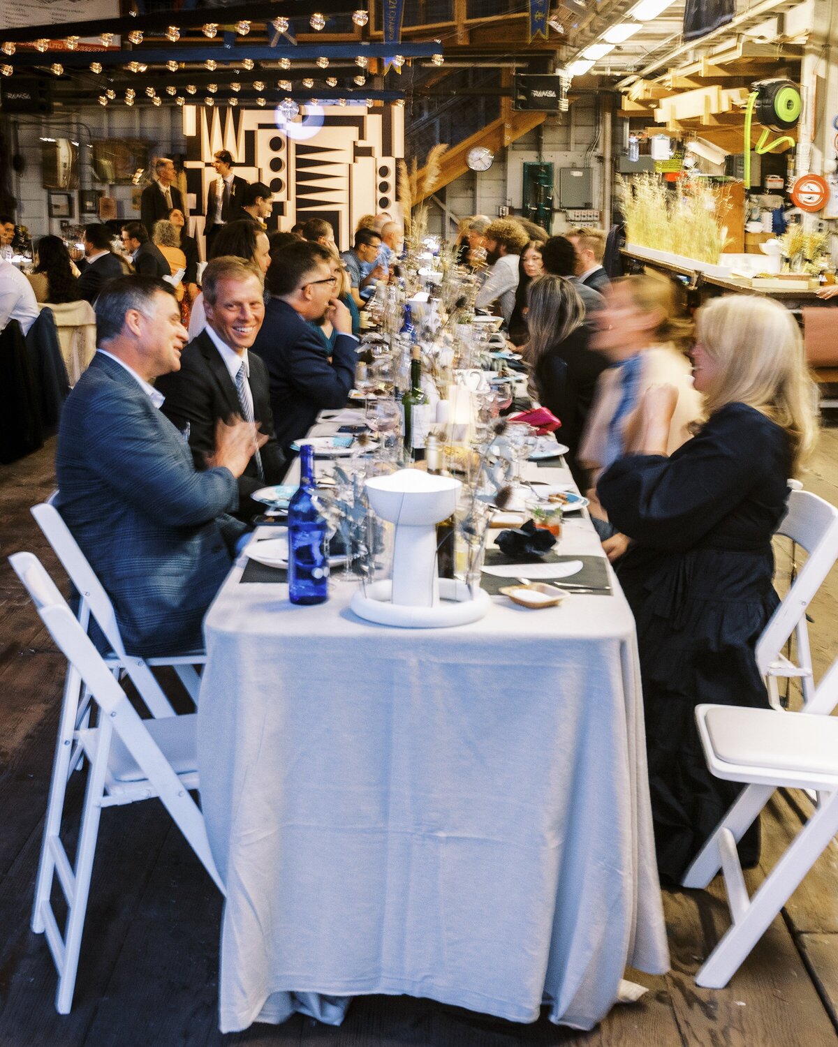 Wedding guests enjoy their dinner at long banquet tables in a converted boatyard in Sausalito
