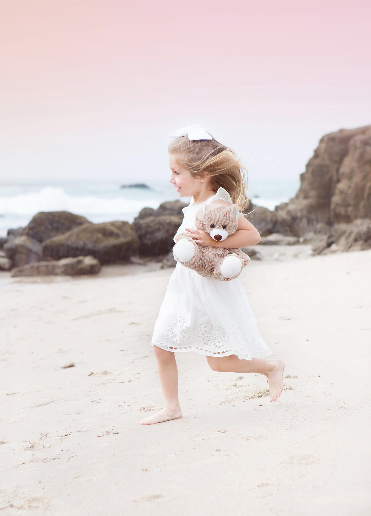Little girl running through the sand at a Malibu park while holding her teddy - Los Angeles Children’s Photographer