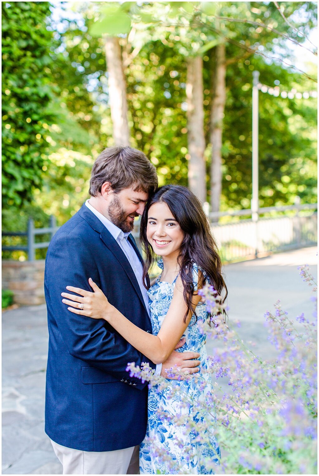 engaged couple hugging with purple florals beside them at the north carolina arboretum