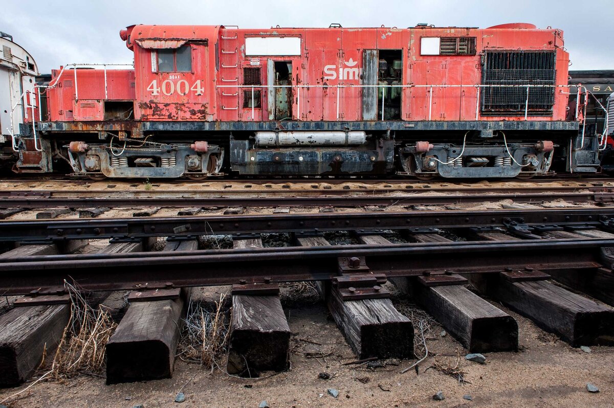 A red train engine rusted with railroad tracks in foreground