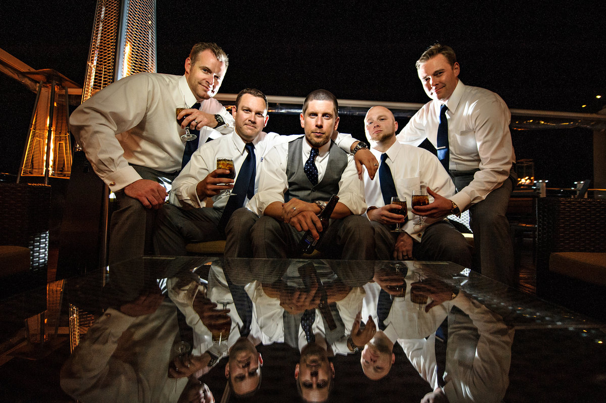 A groom and his groomsmen having a drink on the balcony of his wedding venue.