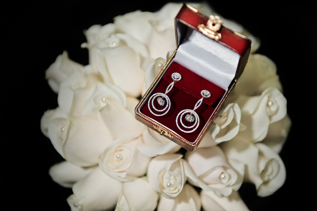 Elegant earrings in a box on top of the white floral bouquet