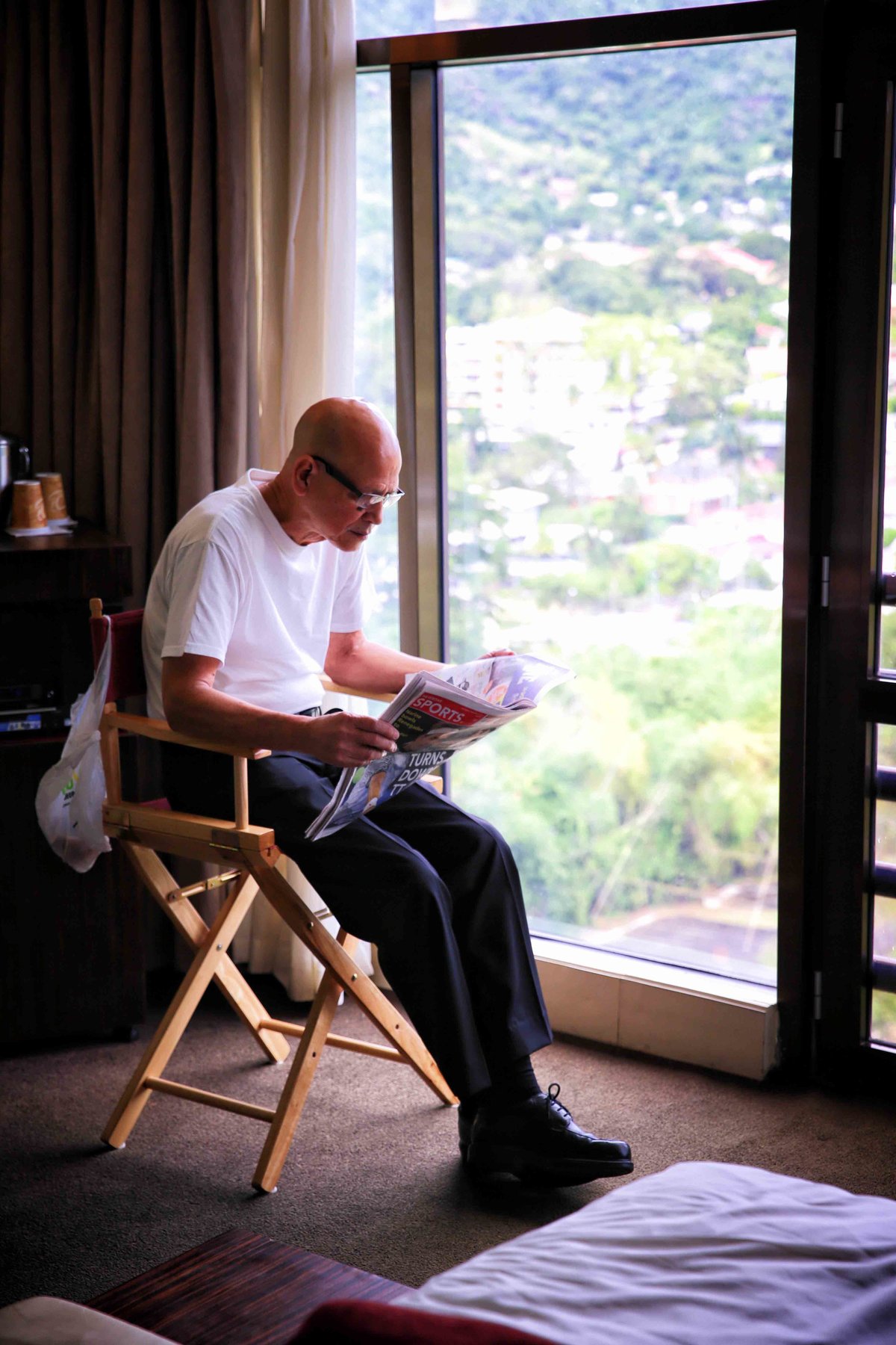 Father of the bride reading the newspaper as the family gets ready for the wedding. Photo by Ross Photography, Trinidad, W.I..