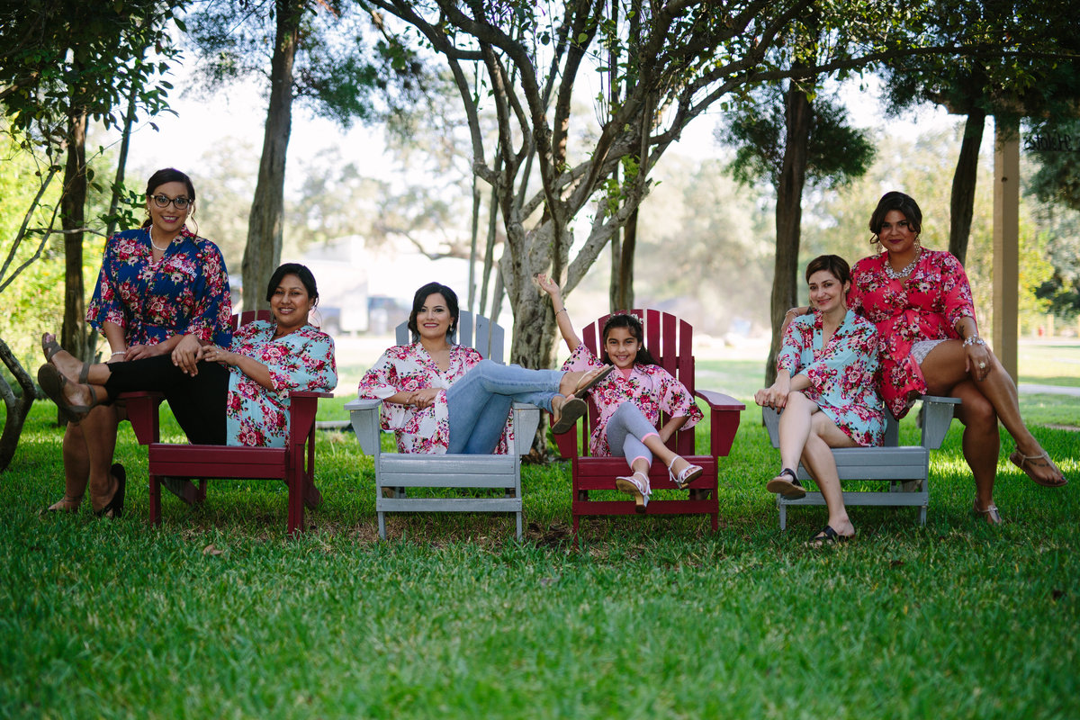 Bride and bridesmaids sitting outside in matching robes before wedding ceremony at The Gardens at old Town Helotes