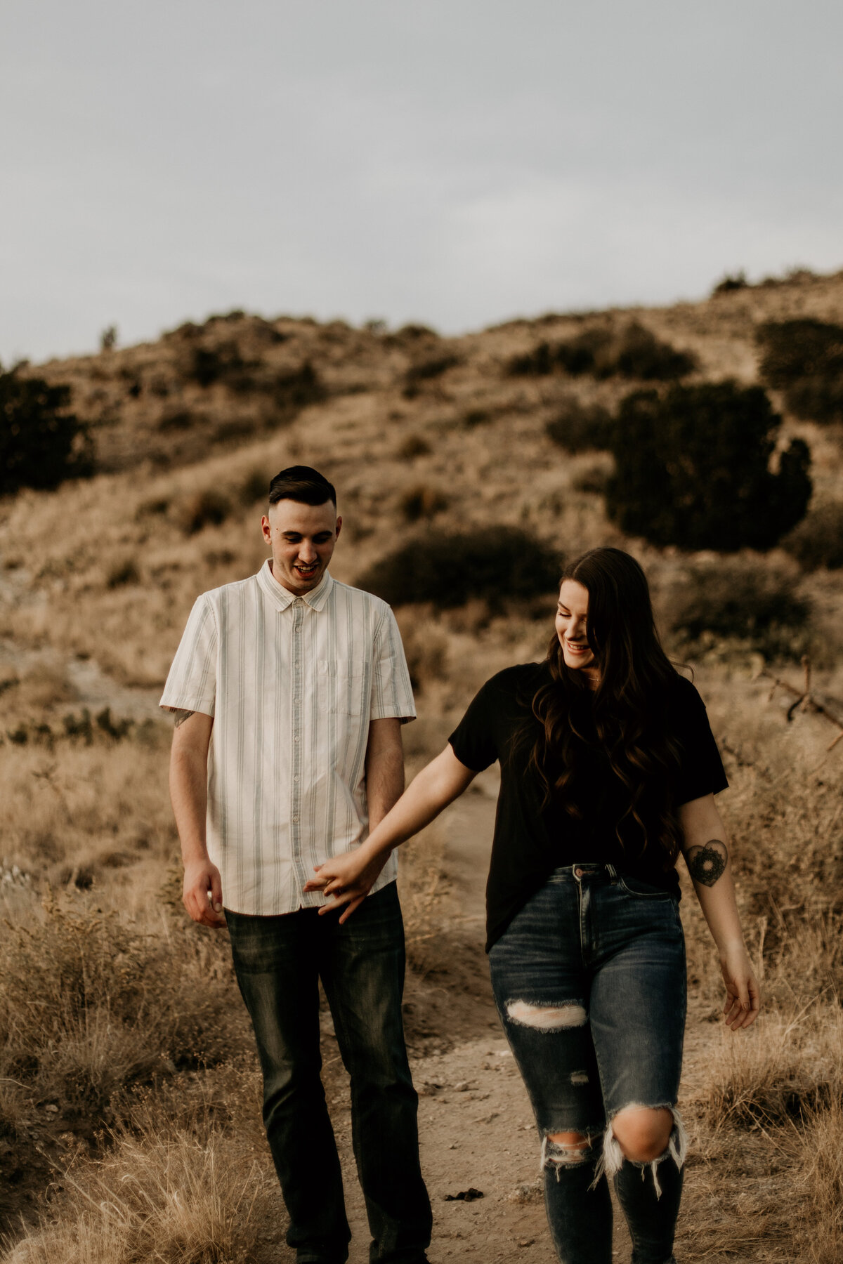 man and woman holding hands walking in the desert