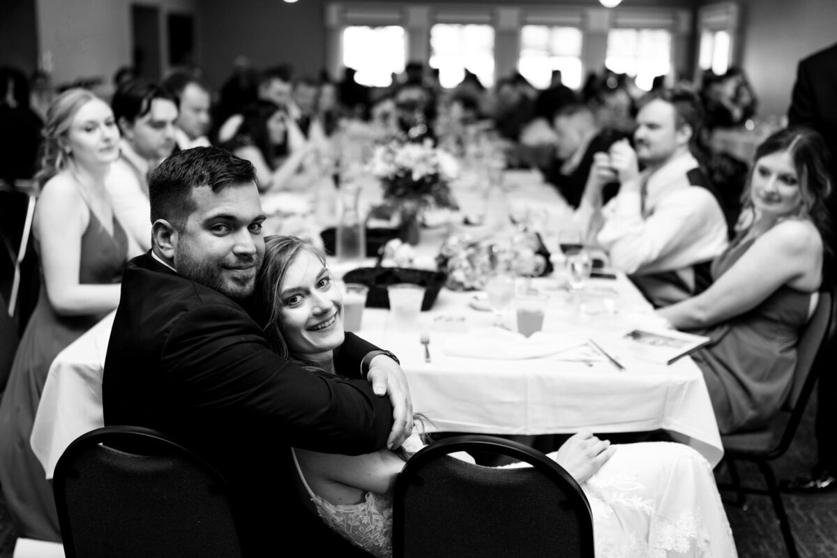 Bride and groom snuggle at the end of the head table.