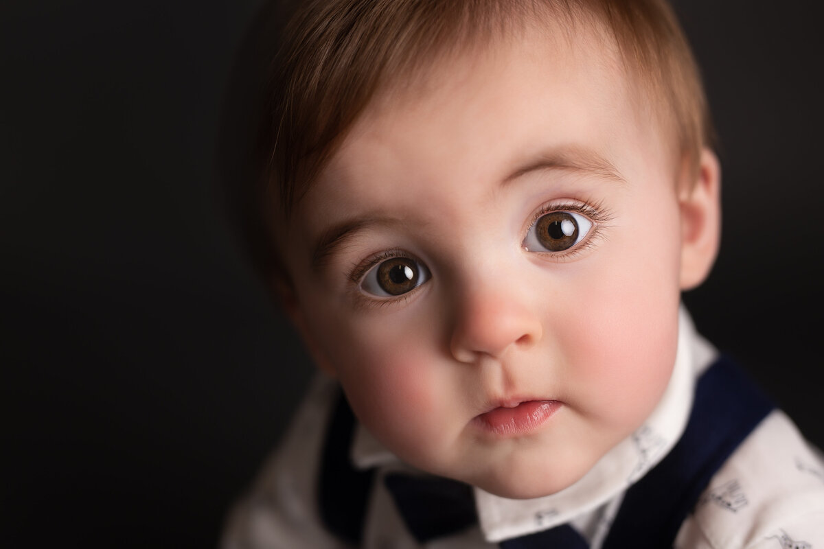 Close up of baby boy looking into the camera with big bright brown eyes.