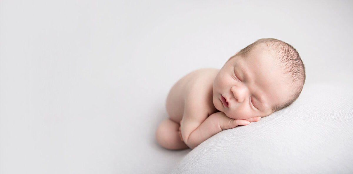 sleeping newborn baby on light grey fabric